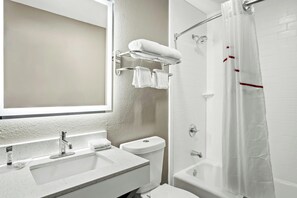 A bathroom with a sink, toilet, and shower area. - Regency Inn & Suites DFW (Euless)