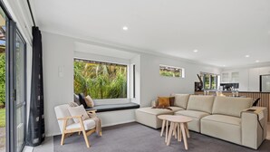 A modern living room with a sectional sofa, a small round table, and a window seat.