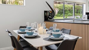 A dining area with a table set for four, featuring blue and white dinnerware, clear wine glasses, and a white candle.