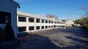 A long, white building with multiple windows and a parking lot in front. - Days Inn Attleboro (Attleboro)