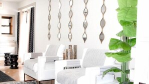 A modern living room with a white sofa set, a patterned rug, decorative wall mirrors, and a large green plant. - Days Inn Attleboro (Attleboro)