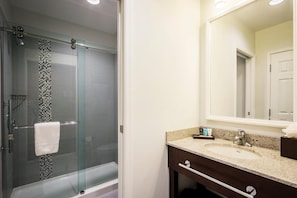 A bathroom with a glass-enclosed shower, a sink, a mirror, and a towel rack. - Nationwide Hotel And Conference Center (Lewis Center)