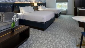 A hotel room with two beds, a large abstract painting on the wall, a desk with a lamp, and a window with a view. - Nationwide Hotel And Conference Center (Lewis Center)