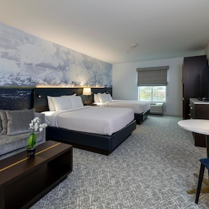 A hotel room with two beds, a large abstract painting on the wall, a desk with a lamp, and a window with a view. - Nationwide Hotel And Conference Center (Lewis Center)
