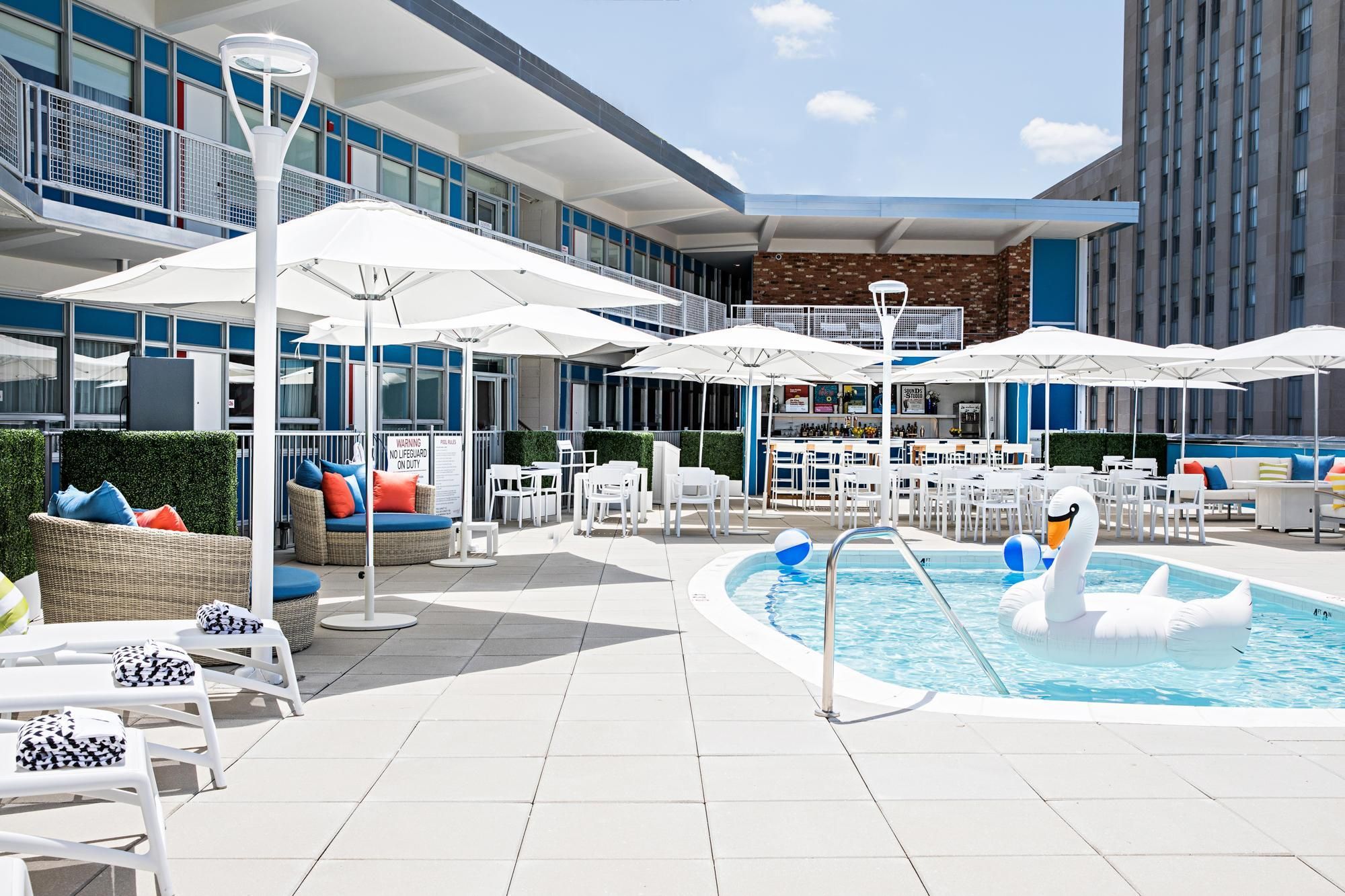 A rooftop pool area with lounge chairs, umbrellas, and a bar.
