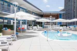 A rooftop pool area with lounge chairs, umbrellas, and a bar. - Unscripted Durham (Durham)