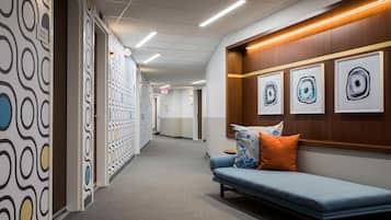 A hallway with patterned walls, a blue sofa with pillows, and framed artwork on the wall.