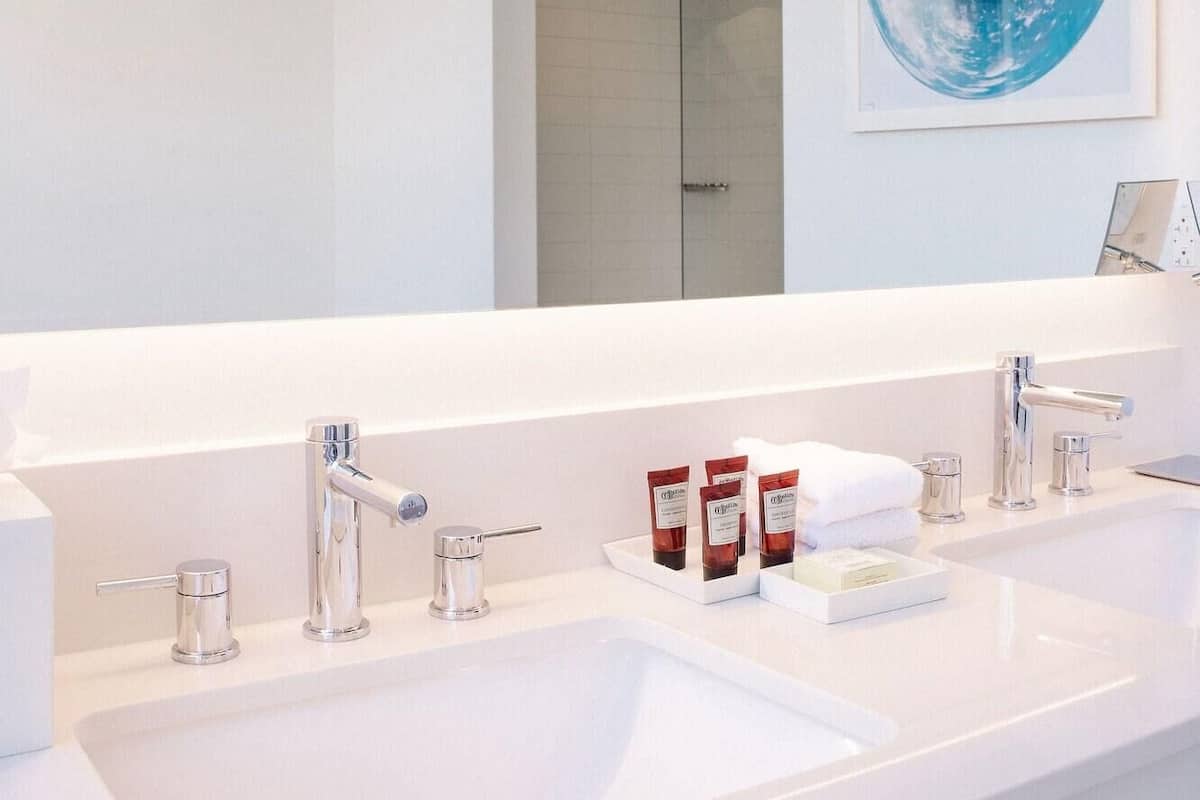 A modern bathroom with a large mirror, two sinks, and a glass shower enclosure.