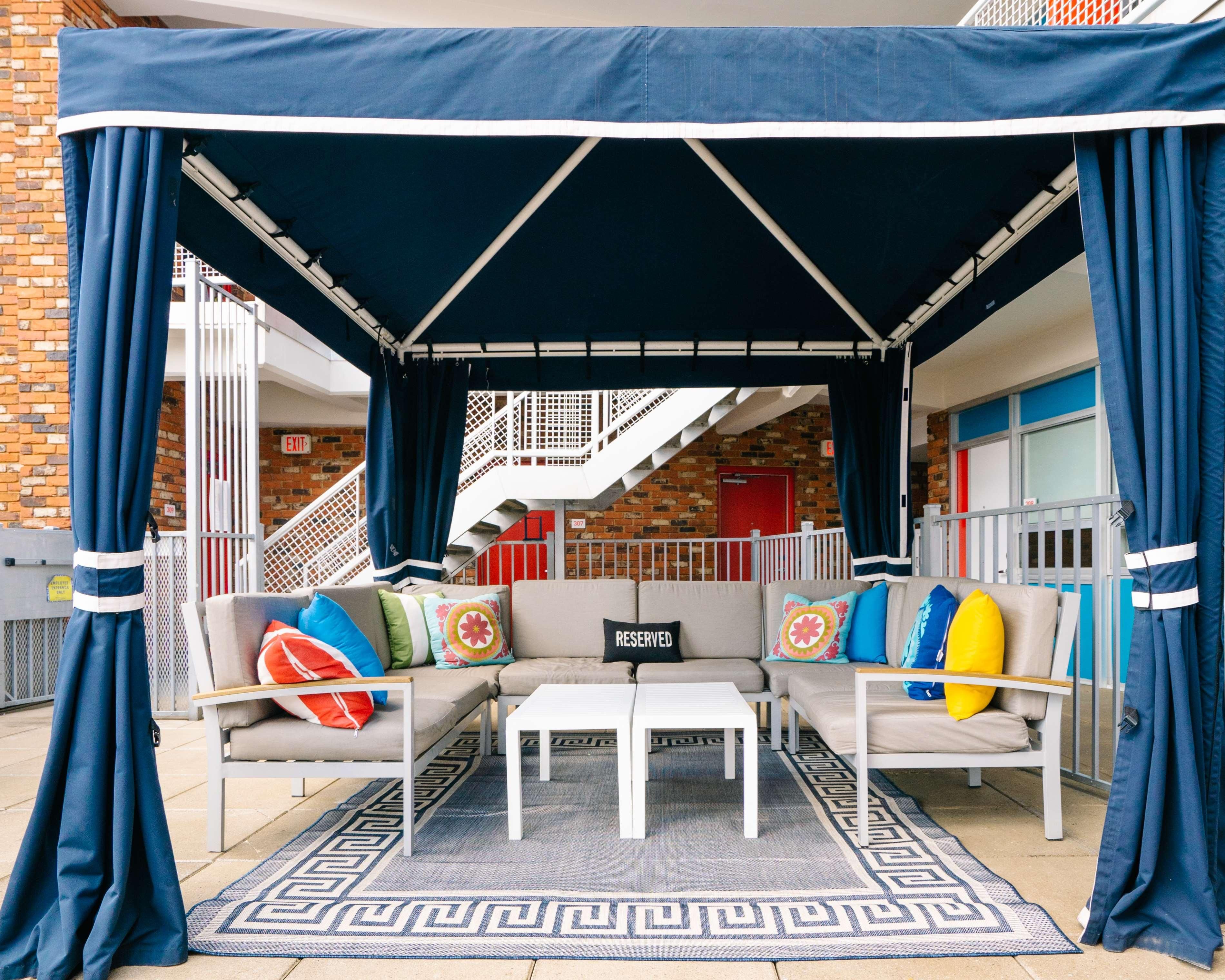 A covered outdoor seating area with a sofa, a coffee table, and a patterned rug.