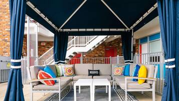 A covered outdoor seating area with a sofa, a coffee table, and a patterned rug.