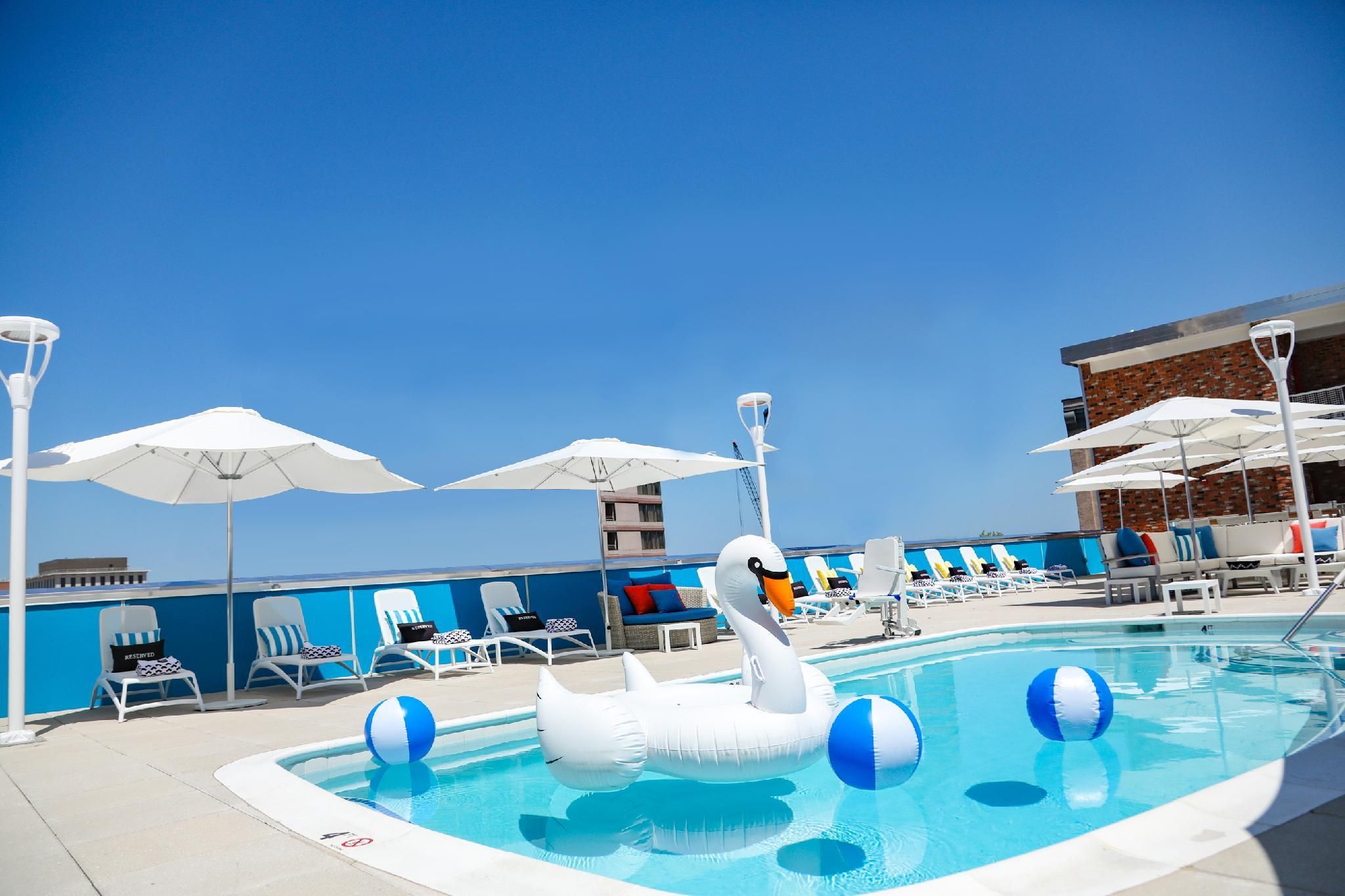 A swimming pool with a swan float, lounge chairs, umbrellas, and a view of the ocean.