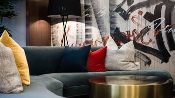 A modern living room with a grey sofa, multiple cushions, a black floor lamp, and a round metallic coffee table.