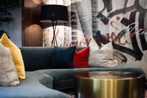 A modern living room with a grey sofa, multiple cushions, a black floor lamp, and a round metallic coffee table. - Unscripted Durham (Durham)