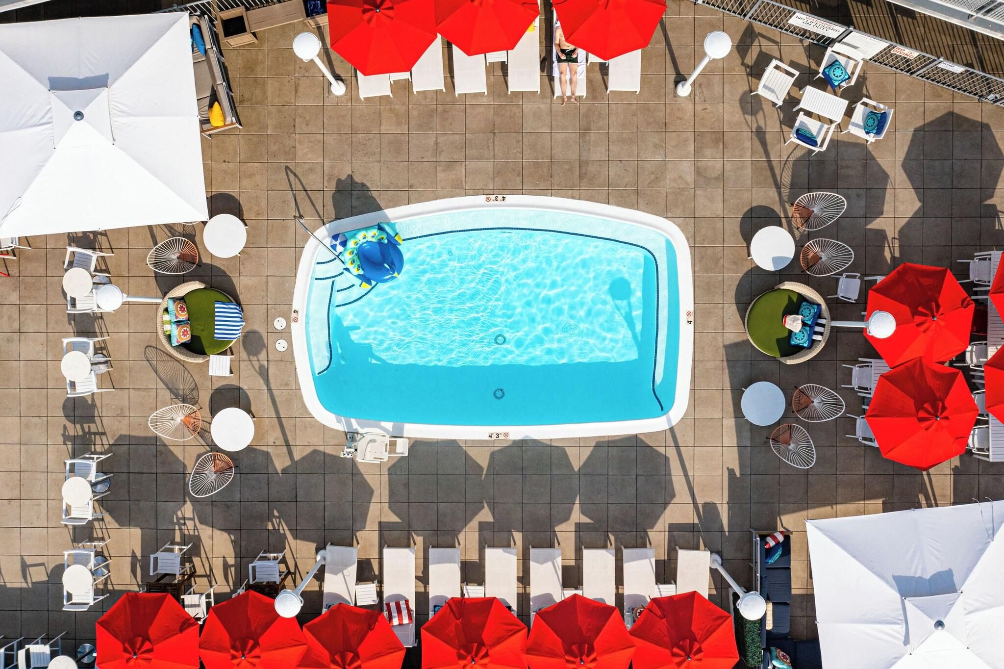 An aerial view of a swimming pool surrounded by lounge chairs and umbrellas.