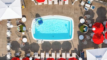 An aerial view of a swimming pool surrounded by lounge chairs and umbrellas.