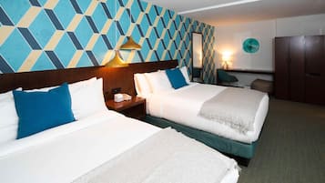 Une chambre d’hôtel avec deux lits, un grand mur orné d’un motif géométrique, un miroir, un bureau avec une lampe et une armoire.