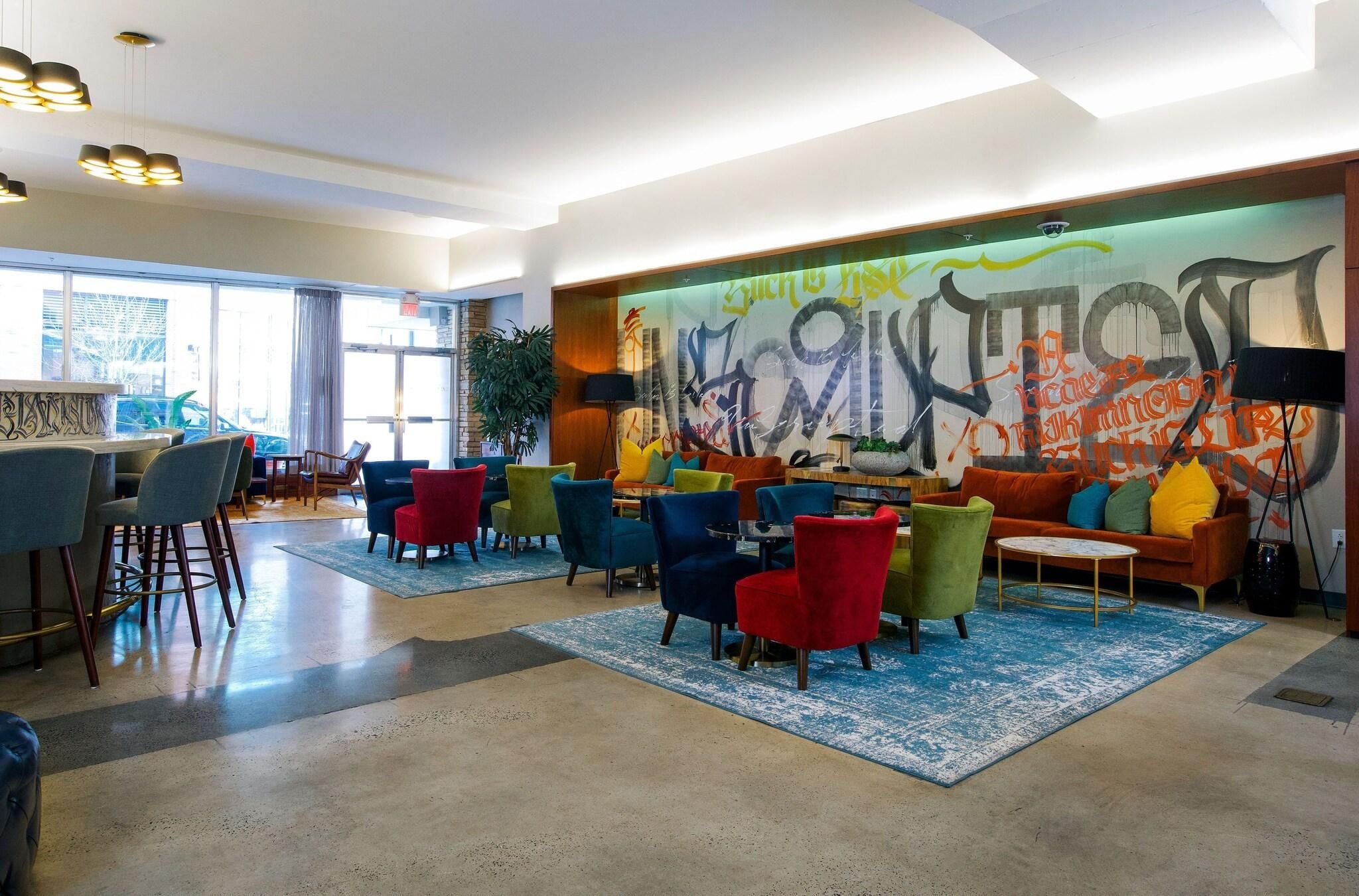 A modern lounge area with colorful chairs, a sofa, and a graffiti wall.