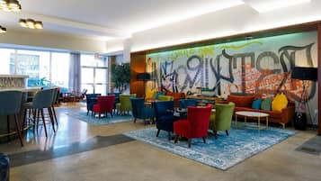 A modern lounge area with colorful chairs, a sofa, and a graffiti wall.