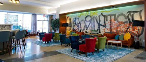 A modern lounge area with colorful chairs, a sofa, and a graffiti wall.