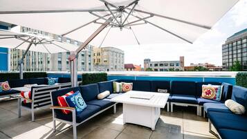 An outdoor seating area with a white table, blue sofas, and a large umbrella.