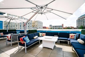 An outdoor seating area with a white table, blue sofas, and a large umbrella. - Unscripted Durham (Durham)