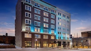 Un hotel de varios pisos con fachada oscura, ventanas amplias y señalización iluminada.