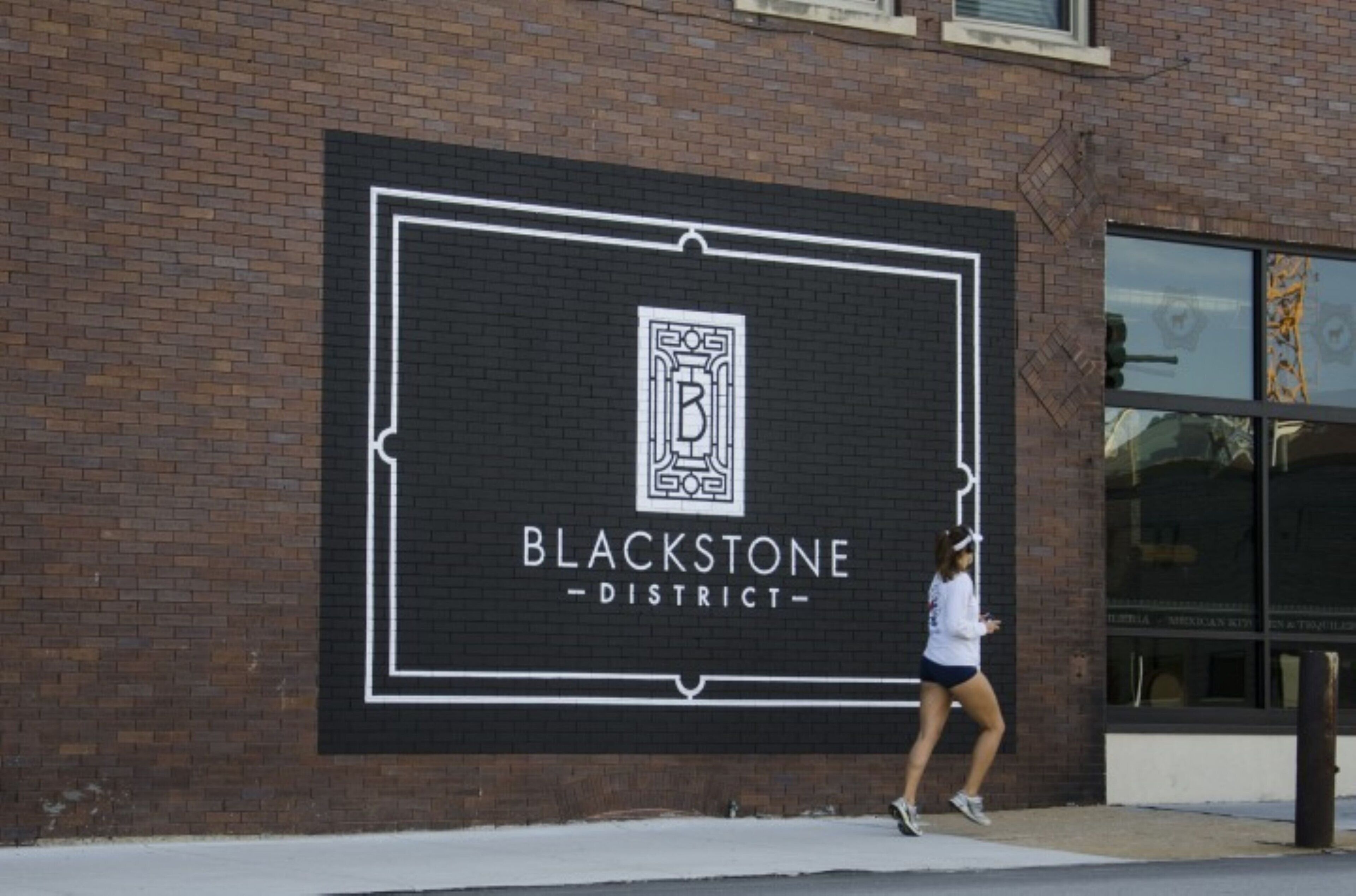 Un bâtiment en briques sur lequel est apposée une grande enseigne indiquant « QUARTIER BLACKSTONE ».