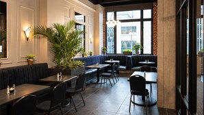 L’intérieur d’un restaurant, avec des banquettes, des tables et des plantes en pot.