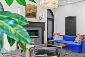 Una sala de estar moderna con chimenea, un sofá azul y una mesa de centro.