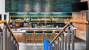 Un espace bar avec un comptoir, des tabourets et un mur en briques.