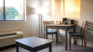 A small dining area with a table and chairs, a floor lamp, and a coffee maker. - Howard Johnson Inn Tybee Island Savannah Ga (Tybee Island)