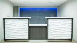 A reception area with two counters, a blue decorative wall, and a tiled floor. - Howard Johnson Inn Tybee Island Savannah Ga (Tybee Island)