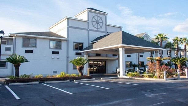 A hotel with a prominent clock tower, a covered entrance, and a parking lot. - Howard Johnson Inn Tybee Island Savannah Ga (Tybee Island)
