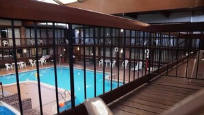 Ein Poolbereich mit Holzterrasse und Liegestühlen, umgeben von einer Brüstung.