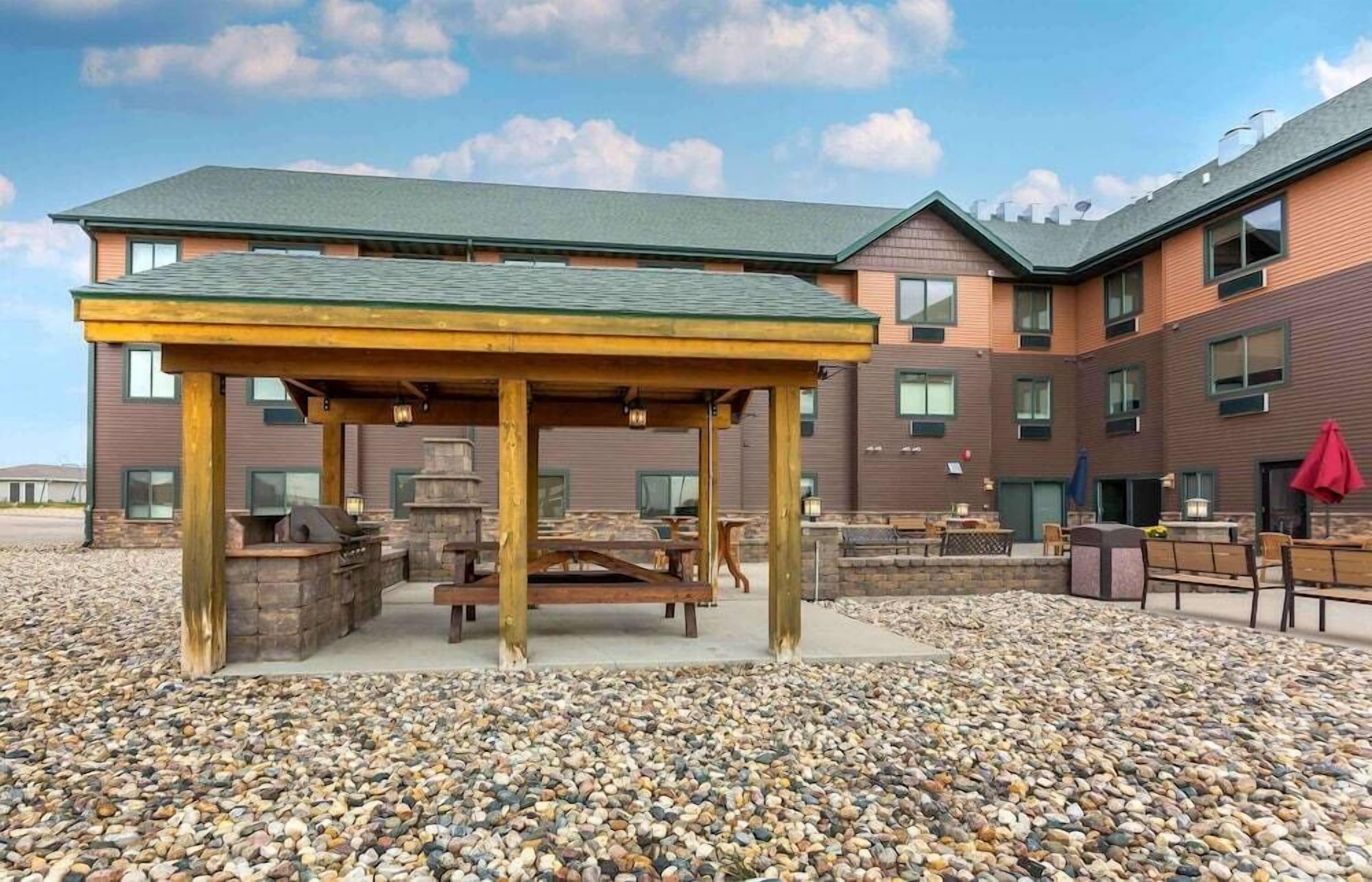 An outdoor patio area with a wooden pergola, barbecue grill, and seating.