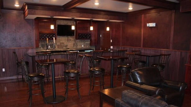 A bar area with wooden walls, a stone countertop, and multiple bar stools.