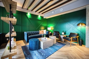 A modern living room with a sofa, chairs, a coffee table, and a lamp. - Hotel Denim (Greensboro)