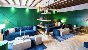 A modern living room with a blue sofa, a coffee table, and a bookshelf. - Hotel Denim (Greensboro)