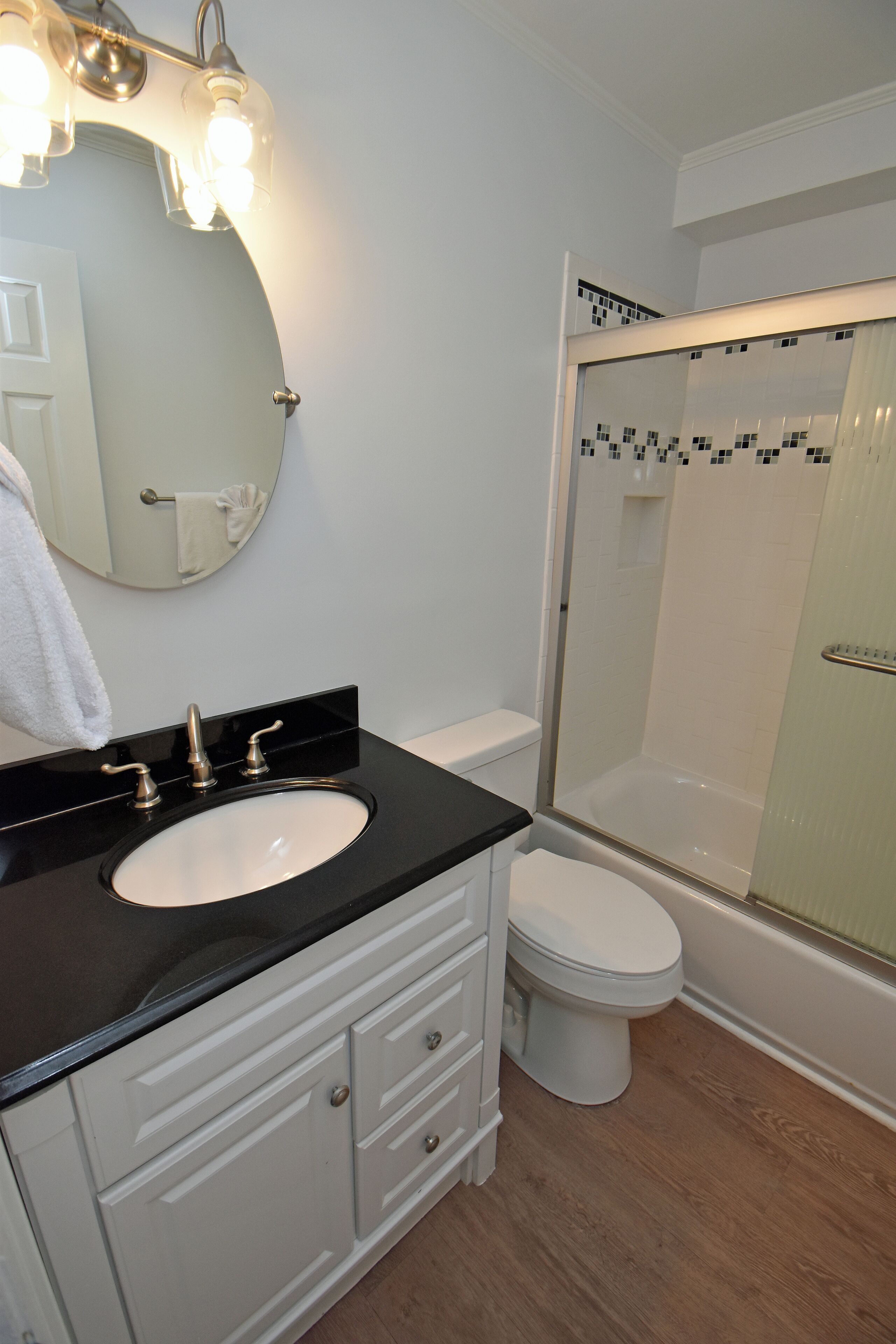Un bagno con uno specchio rotondo, un lavandino, un WC e una doccia con pareti in vetro.