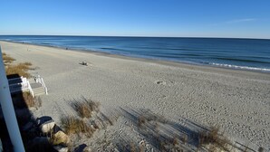 Een strand met heldere lucht, een zandstrand en enkele mensen die wandelen.