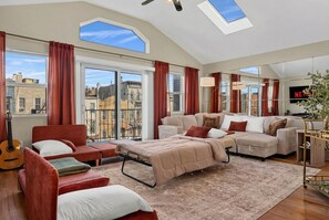 Ein geräumiges Wohnzimmer mit hohen Decken, großen Fenstern und einer gemütlichen Sitzecke.