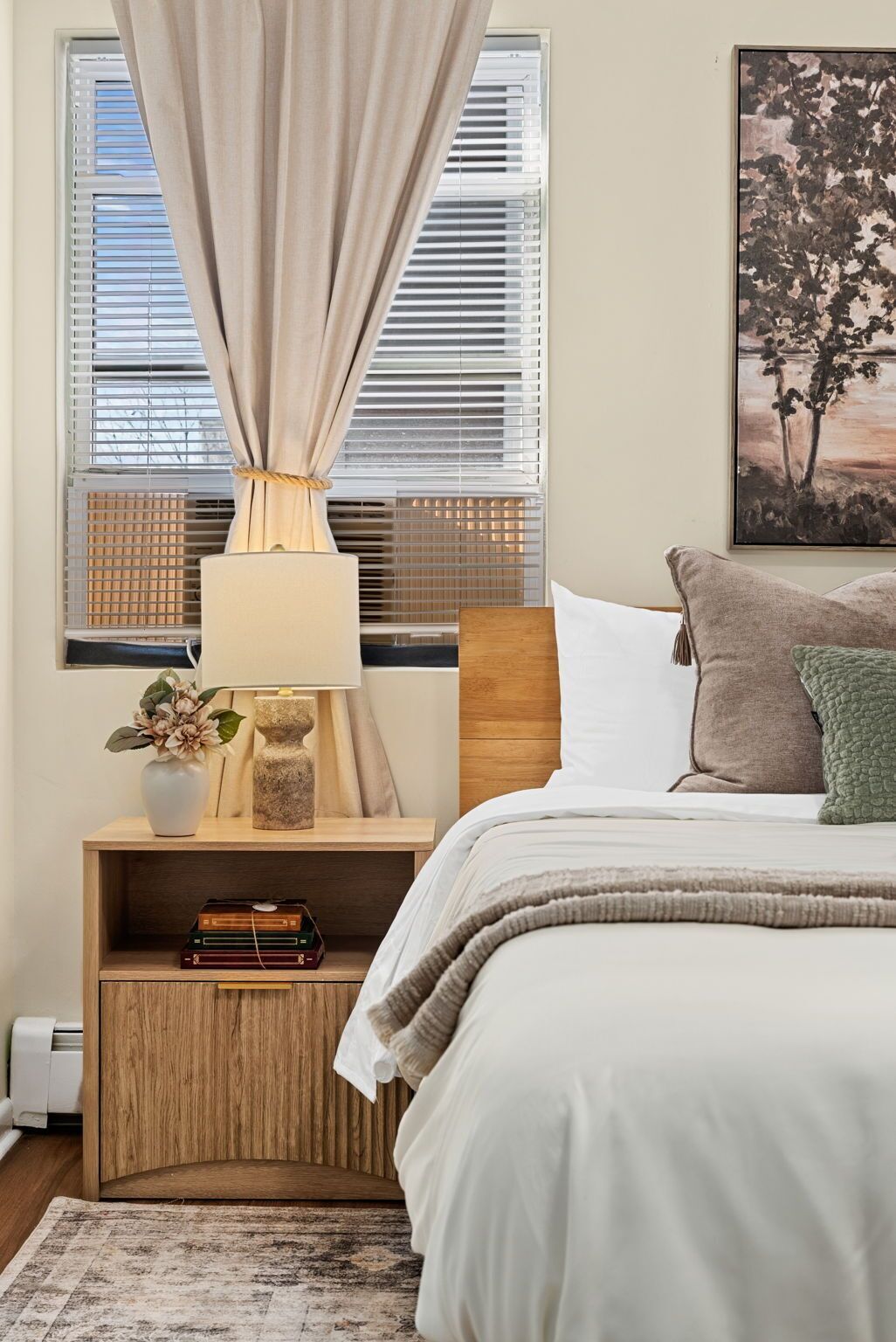 Une chambre à coucher avec un lit, une table de chevet, une lampe et un tableau au mur.