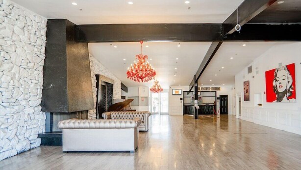 A spacious lobby with a stone wall, a large white sofa, a grand chandelier, and a reception desk.