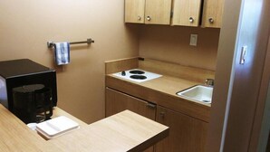A compact kitchenette with a stove, sink, and cabinets.