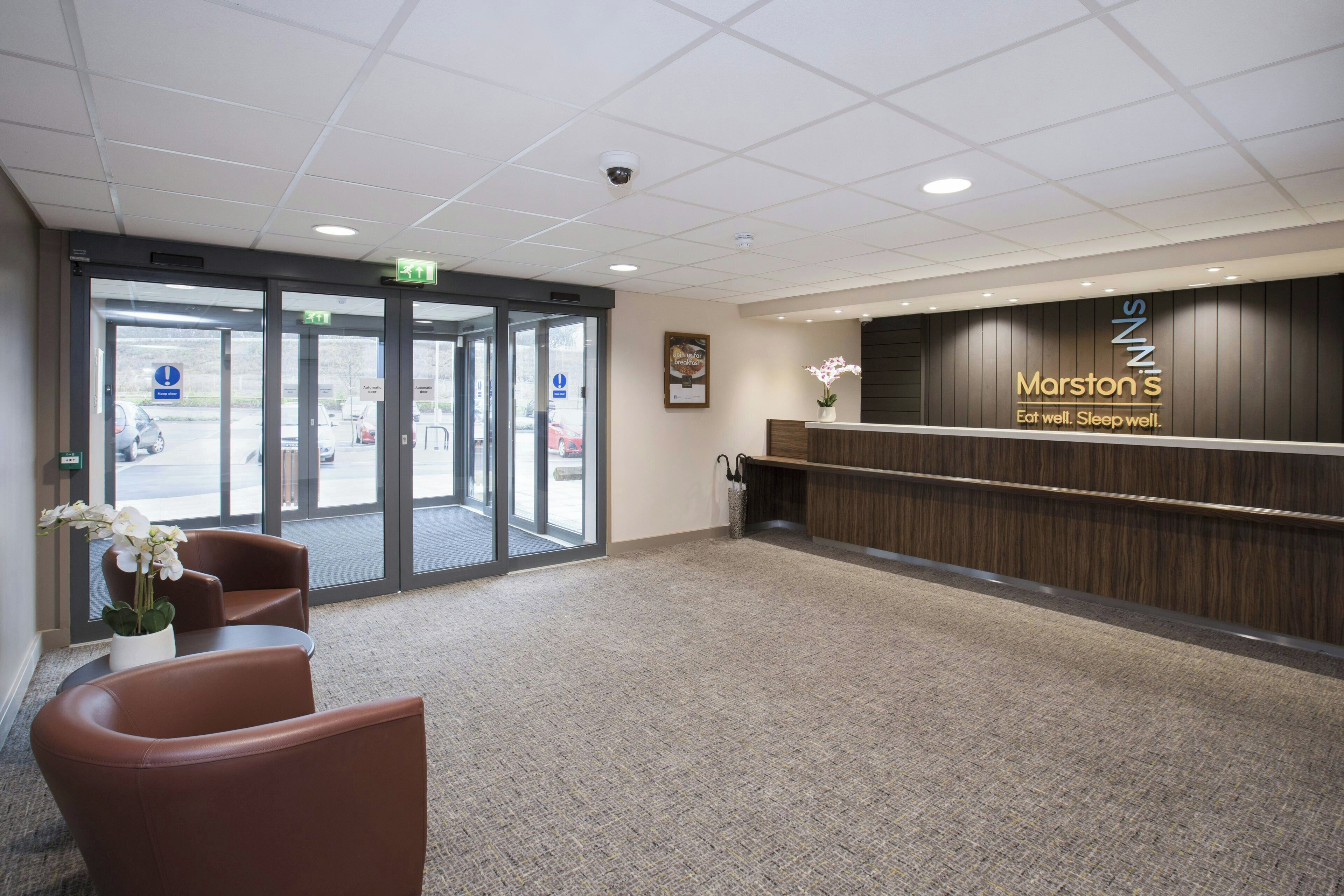 A reception area with a wooden reception desk, a framed picture on the wall, and a potted orchid.