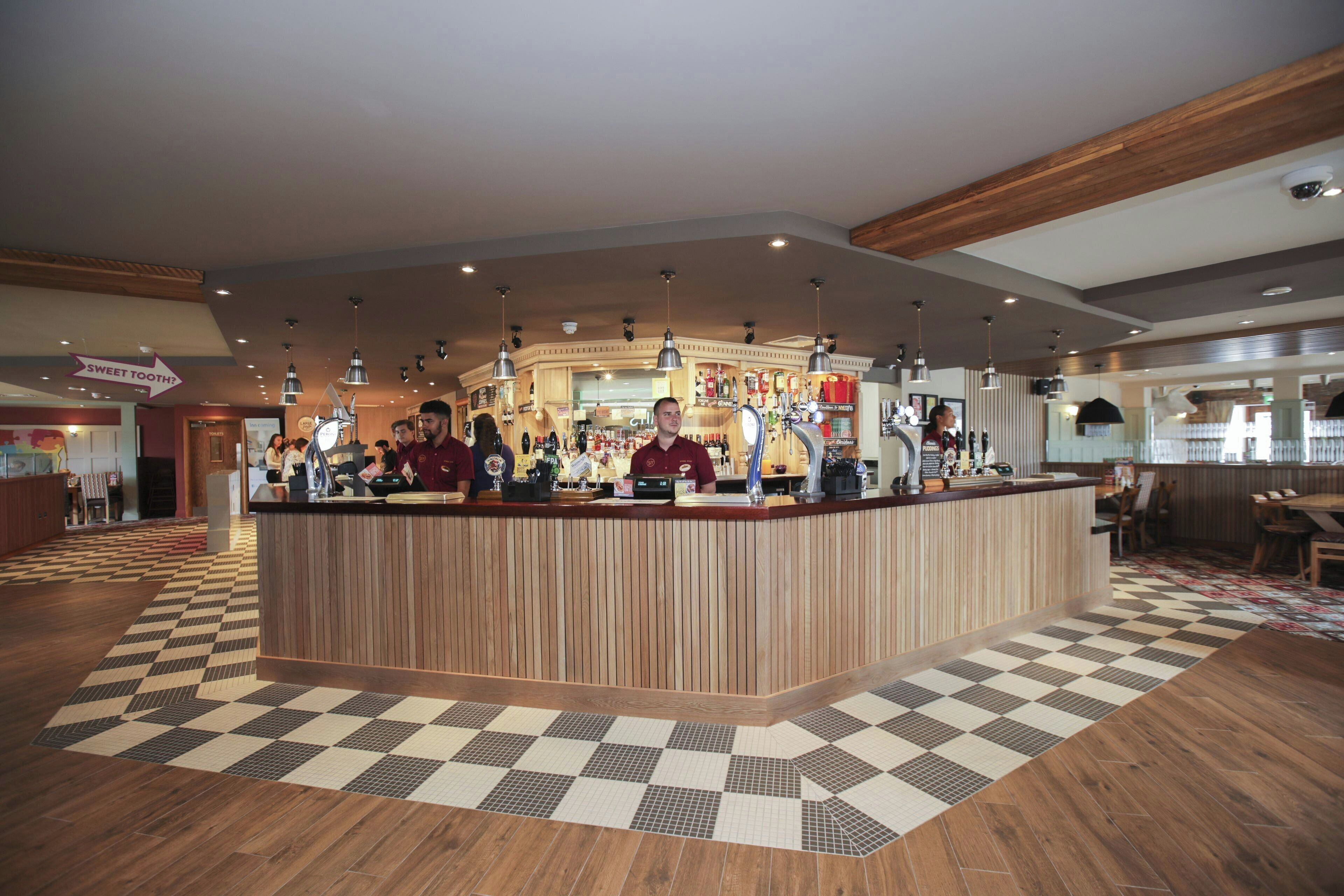 A reception area with a checkered floor, wooden reception desk, and multiple bar counters.