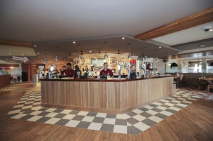 A reception area with a checkered floor, wooden reception desk, and multiple bar counters.