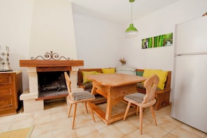 Un salon chaleureux avec une cheminée, des meubles en bois et un luminaire suspendu vert.