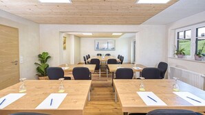 A conference room with wooden tables, black chairs, and a large window with plants. - Interest of Bavaria (Oberstaufen)