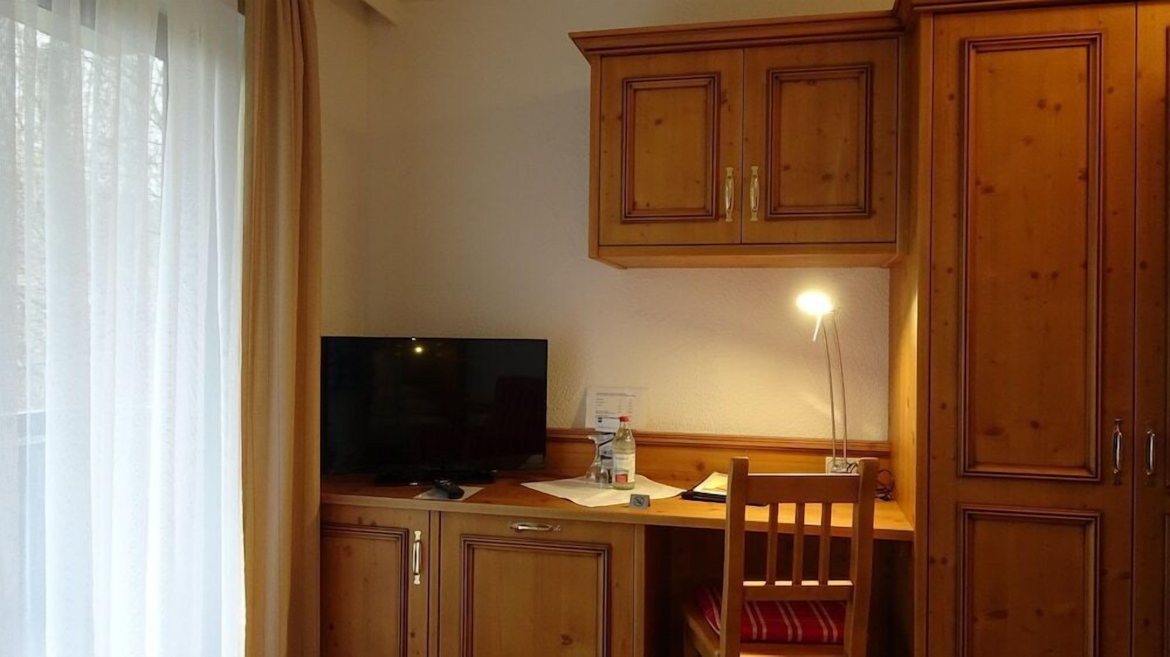 Eine Holzküchenzeile mit Fernseher, einem Stuhl und einem Schreibtisch.
